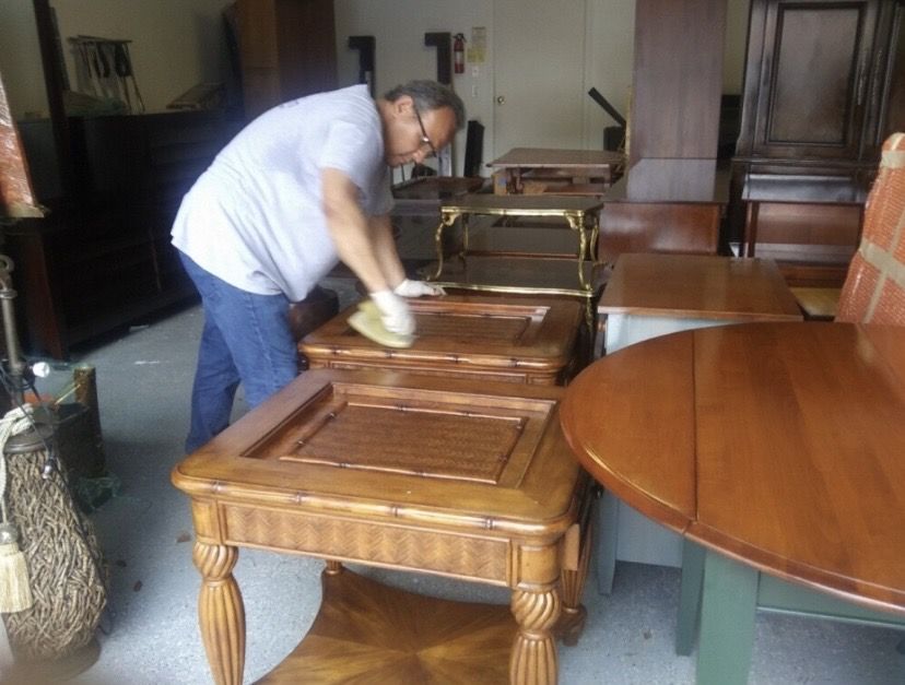Magnolia technician hand-cleaning wood furniture in storage